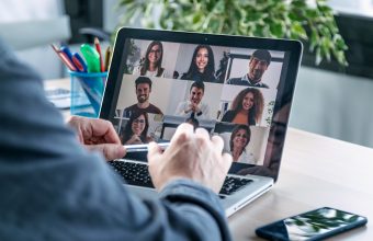 Back view of male employee speaking on video call with diverse colleagues on online briefing with laptop at home.